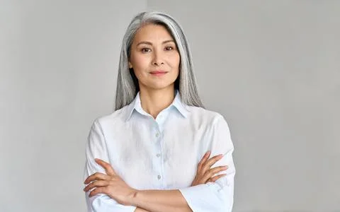 Headshot of mature 50 years old Asian business woman on grey background. Stock Photos