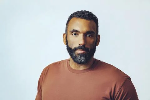 Headshot portrait of a handsome bearded mid adult man looking at camera against Stock Photos