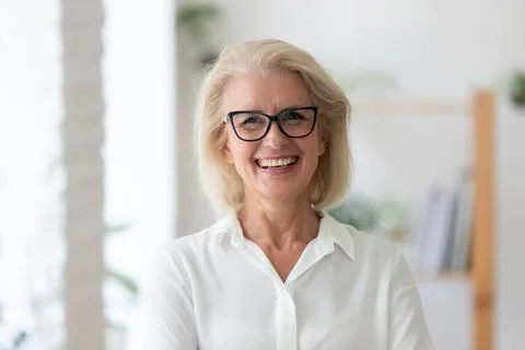 Headshot portrait of smiling senior businesswoman in office Stock Photos