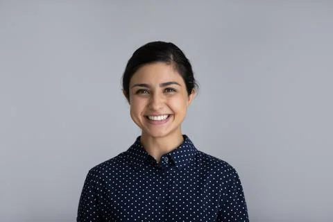Headshot portrait of smiling young Indian woman on grey background Stock Photos
