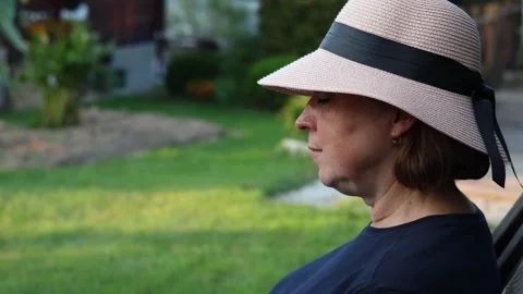 Headshot profile of pretty middle aged woman in the hat sitting in the garden Stock Footage 288241318