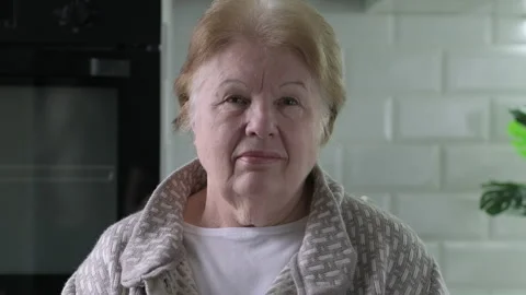Headshot video portrait of smiling senior woman sitting at home in the Kitchen Stock Footage 169123761