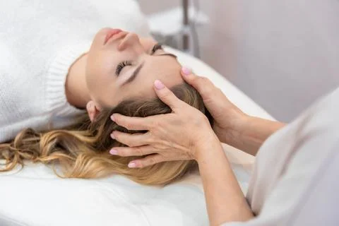 Healer performing by lightly touched access bars therapy on young woman head Stock Photos