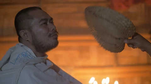 Healing ritual in magic house. Witch blowing fan to sick man while healing Stock Footage 103401066