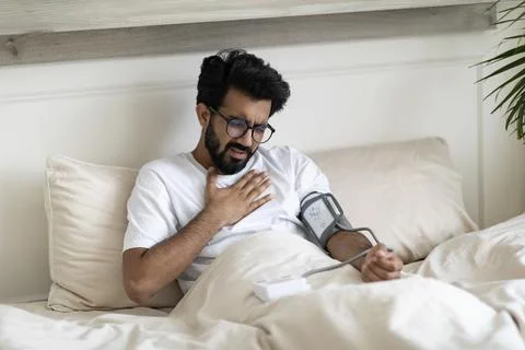 Health Problems. Indian Guy Having Chest Pain At Home, Checking Blood Pressure Foto stock