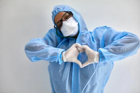 Health professional in hazmat suit N95 mask and surgical gloves makes heart sign Stock Photos