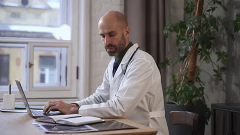 Health specialist using device in workflow and sitting at table in clinic office Stock Footage 172136625