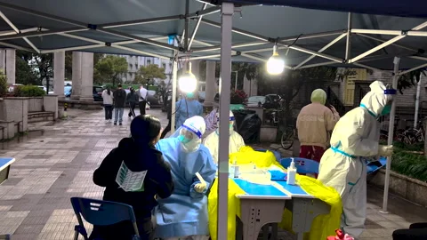 Health workers in hazmat doing compulsory PCR tests for residents under lockdown Stock Footage 242742283