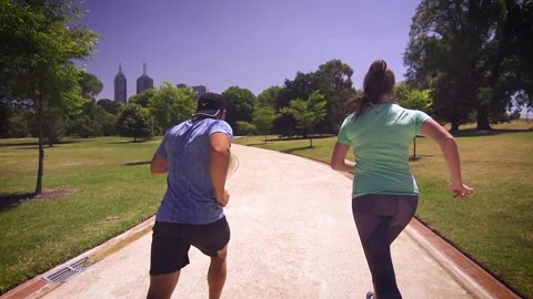 Healthy &amp; active couple running / jogging in slow motion in a park Stock Footage 132241235