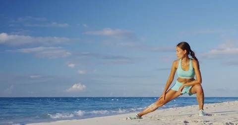 Healthy active lifestyle woman stretching legs before running on beach run Stock Footage
