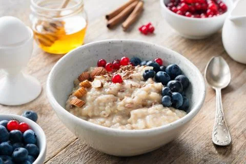 Healthy breakfast food oatmeal porridge, boiled egg, honey and berries. Stock Photos