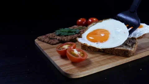 Healthy breakfast. A man is putting scrambled eggs on a fresh grain bread 스톡 동영상 99656366