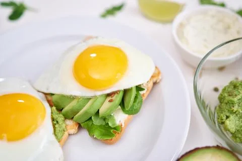 Healthy breakfast or snack - sliced avocado and fried egg on toasted bread Stock Photos