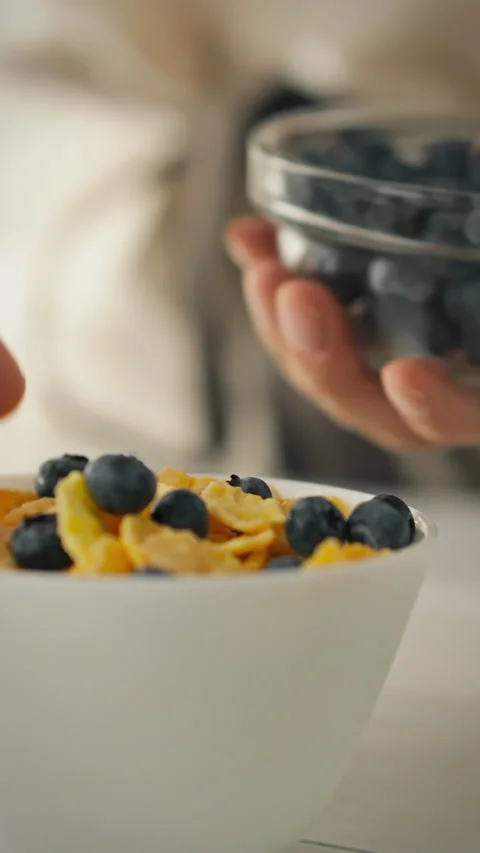 Healthy breakfast preparation with berries and cereal in a bright kitchen Stock Footage 331593635