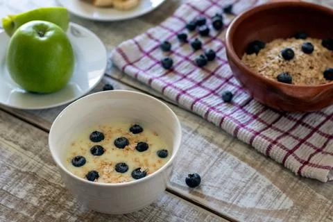 A healthy breakfast on the rustic table: yogurt, oats, blueberries, apples,.. Stock Photos
