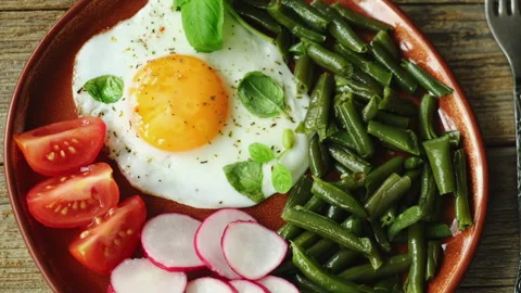 Healthy breakfast. Vegetables and fried egg garnished with fresh basil leaves Stock Footage 340332973