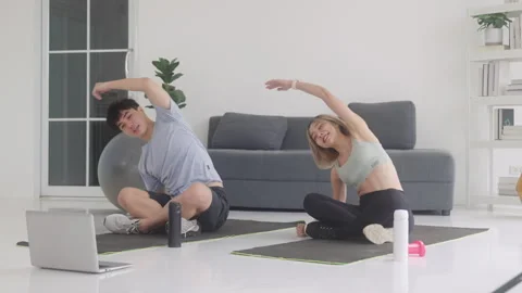 Healthy couple exercising at home, using laptop Video stock 248586205