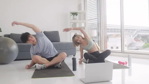 Healthy couple exercising at home, using laptop Stock Footage 248586216
