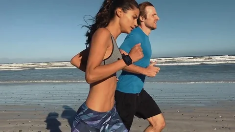 Healthy couple running on beach Stock Footage 76520569