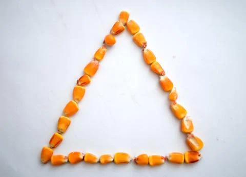 Healthy ecological corn in the form of a triangle on a white background Stock Photos