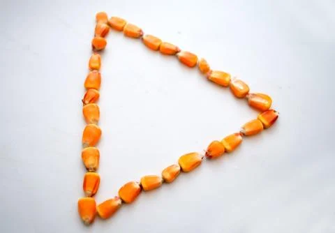 Healthy ecological corn in the form of a triangle on a white background Stock Photos