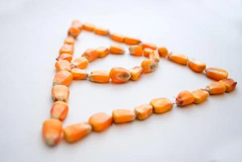 Healthy ecological corn in the form of a triangle with an eye on a white back Stock Photos