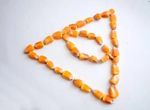 Healthy ecological corn in the form of a triangle with an eye on a white back Stock Photos