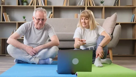 Healthy elderly 60s couple learning to meditate, watching online yoga tv Stock Footage 252681078