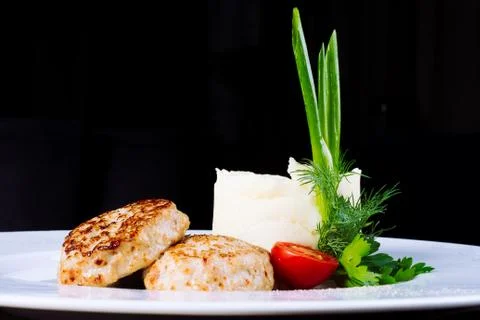 Healthy food. Cutlets with mashed potatoes in a white plate on a black Stock Photos