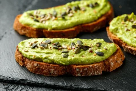 Healthy Homemade Avocado creamy Toast with nuts mix on rustic stone board Stock Photos