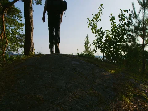 Healthy man with large backpack walks on the mountain by the sea at sunset Stock Footage