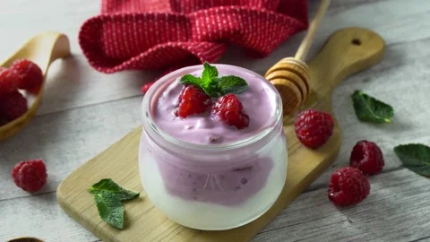 Healthy raspberry yoghurt garnished with fresh raspberries. Rotating 4K shot. Video stock 134292349