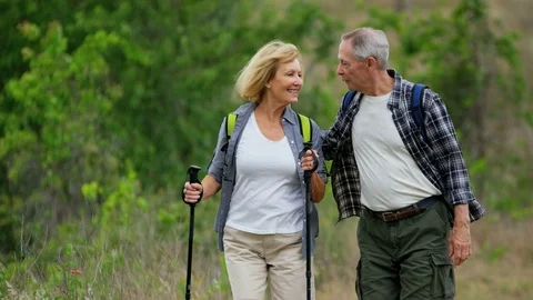 Healthy retired Caucasian American couple enjoying their vacation hiking to keep Stock Footage