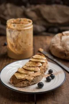 Healthy snack, toasted rustic bread with peanut butter and banana Stock Photos