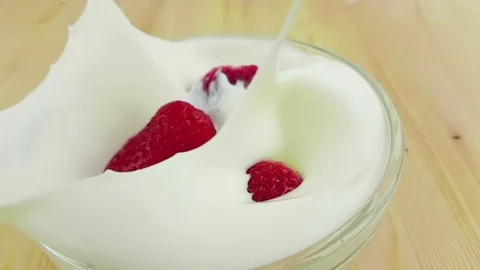 Healthy strawberries falling down in slow motion in to white yogurt on wood Stock Footage 89416135