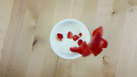 Healthy strawberries falling down on white yogurt in slow motion on wood Stock Footage 89372463