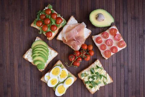 Healthy toast for breakfast with avocado, eggs, tomatoes, arugula etc Stock Photos
