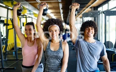 Healthy young athletes doing exercises at fitness studio. Stock Photos