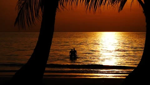 Healthy young couple in beautiful calm ocean on exotic tropical beach at sunset Stock Footage