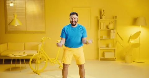 Healthy young man using weight training equipment to exercise while standing at Stock Footage 165864188