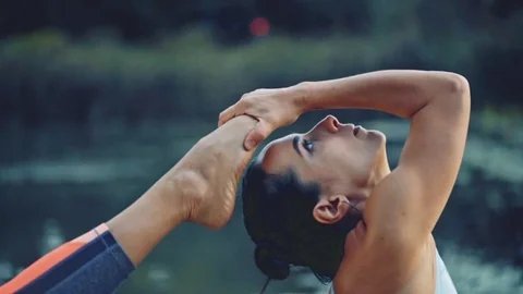 Healthy young woman practicing yoga in the park at sunset Stock Footage