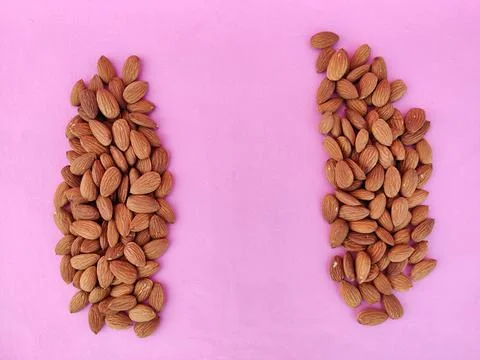 Heap of Almonds separated with copy space in center. Isolated on pink backgro Stock Photos