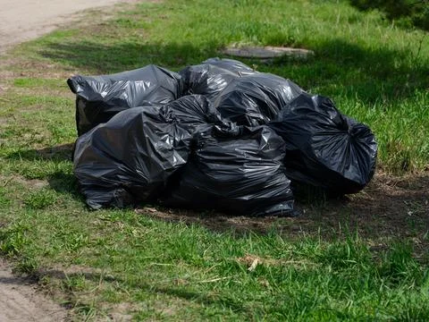 Heap of big black plastic garbage bags full of trash outdoors Stock Photos