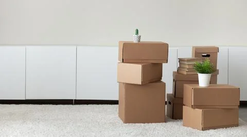 Heap of boxes with belongings stacked in empty living room Stock Photos
