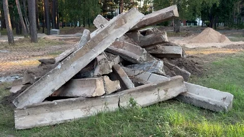 Heap of broken concrete blocks and curbs on grass at a construction site Stockbeeldmateriaal 341830152