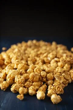 Heap of Caramel Corn on blue rustic table and black background with copy spac Stock Photos