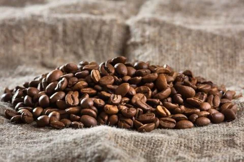 Heap of coffee beans on burlap (selective focus used) Stock Photos