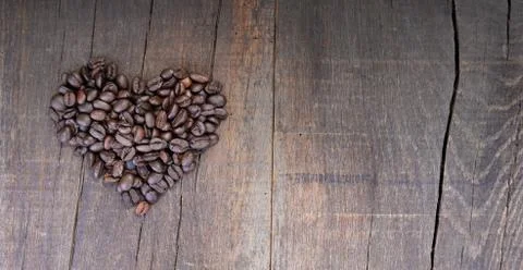 Heap of coffee beans forming a heart on a rustic plank with copy sapce at the Foto stock