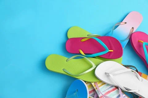 Heap of different flip flops and space for text on blue background, top view. Foto stock