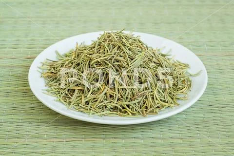 A heap of dry rosemary on a white saucer on a green table mat Stock Photos